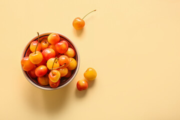 Bowl with sweet yellow cherries on yellow background