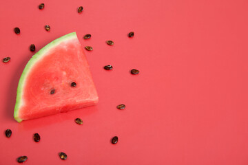 Composition with piece of ripe watermelon and seeds on red background, closeup