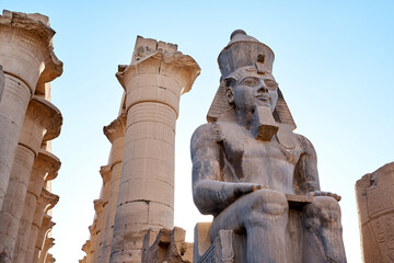 Seated statue of Ramesses II by the First pylon of the Luxor Temple, Egypt. Columns and statues of...