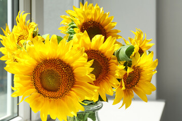Vase with beautiful sunflowers on windowsill in room, closeup
