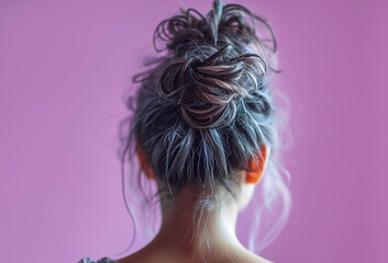 Fototapeta premium Portrait of a woman with violet hair with bun hairstyle close-up, back view.