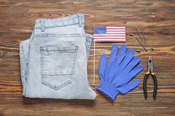 Jeans pants with USA flag, gloves and construction supplies on wooden background. Labor Day celebration