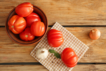 Bowl with fresh ripe tomatoes and different spices on wooden background