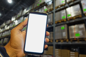 business owner holding phone mock up in warehouse.