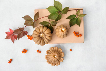 Beautiful autumn composition with burning candles in shape of pumpkin and book on white background