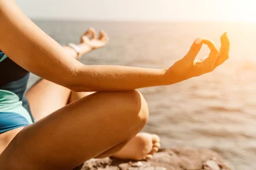 Foto auf Acrylglas Yoga on the beach. A happy woman meditating in a yoga pose on the beach, surrounded by the ocean and rock mountains, promoting a healthy lifestyle outdoors in nature, and inspiring fitness concept. © svetograph