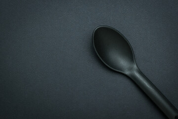 A black silicone spoon on a black background.