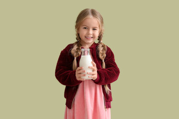 Cute little girl with bottle of tasty milk on green background