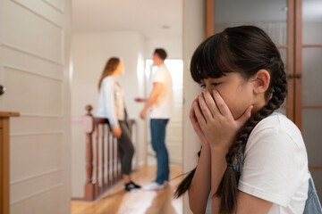 Stressed and unhappy young girl huddle in corner, cover her face while her parent arguing in...