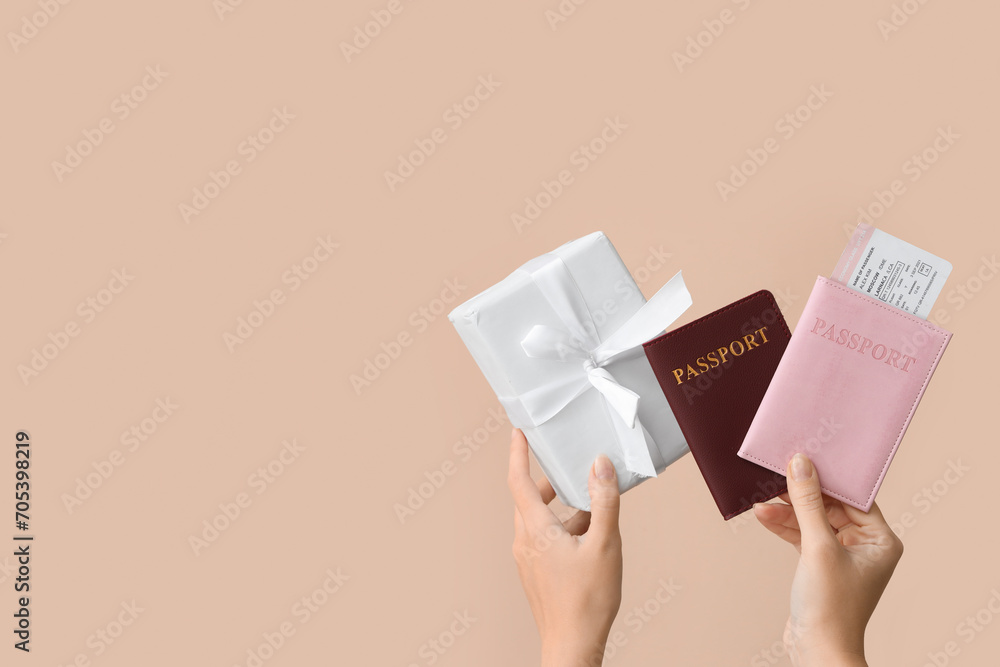 Wall mural female hands holding passports and gift on light background. new year vacation concept