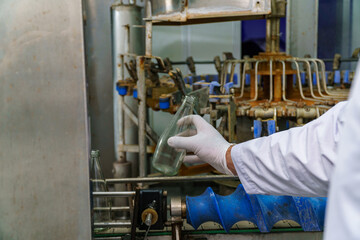 A factory worker inspects bottles on a beverage production line.