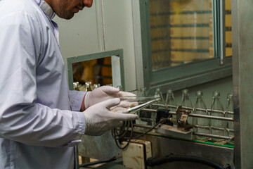 A factory worker inspects bottles on a beverage production line.