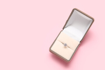 Box with beautiful engagement ring on pink background