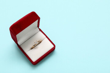Box with beautiful engagement ring on blue background