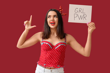 Beautiful young happy pin-up woman holding paper sheet with text GIRL POWER and pointing at...