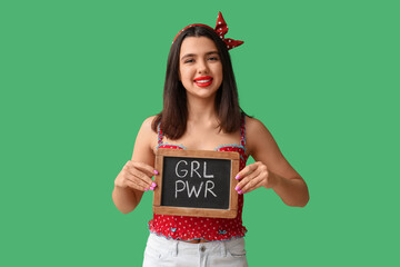 Beautiful young happy pin-up woman holding blackboard with text GIRL POWER on green background