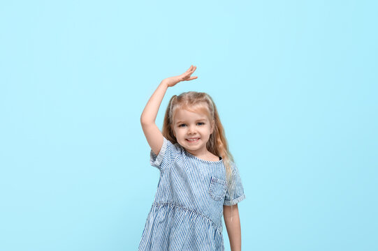 Cute little girl measuring height on blue background