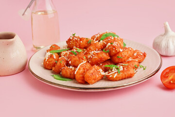 Plate of tasty gnocchi with cheese on pink background