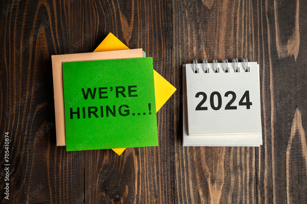 Poster 2024 calendar and a stack of note paper with we're hiring text