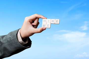 The businessman's hand shows wooden cubes with Hire Me letters