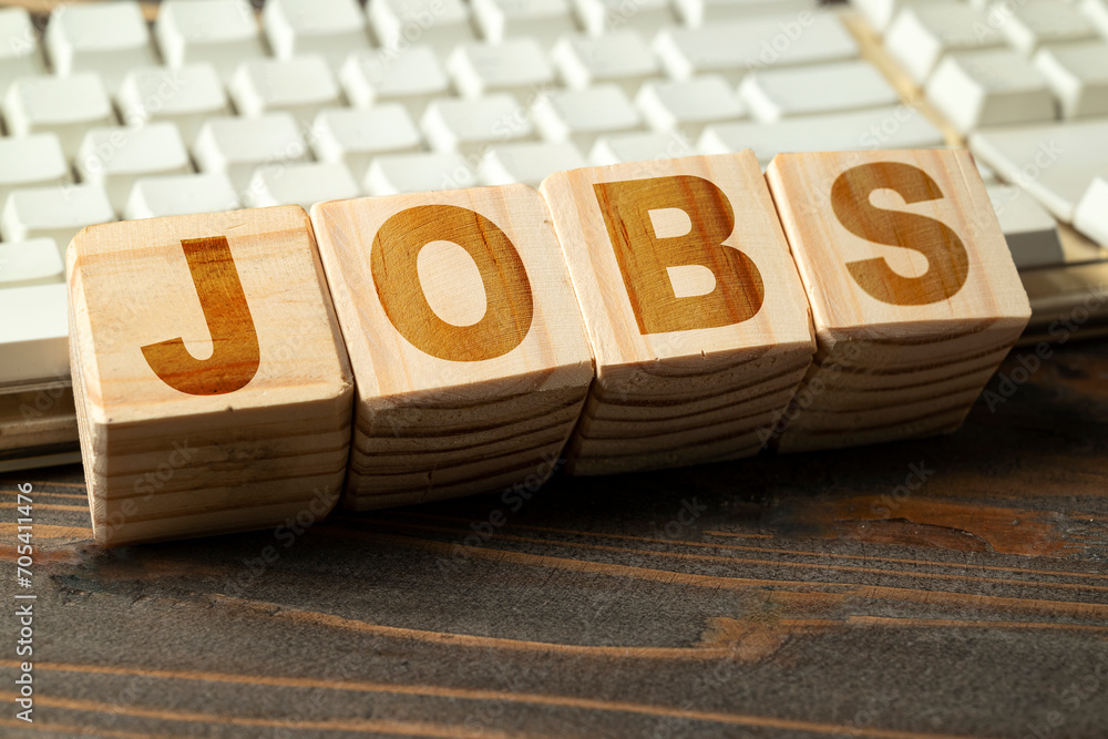Poster closeup view of wooden cubes with jobs text with computer keyboard