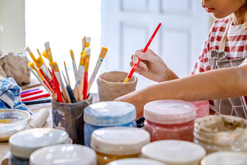 Kids making a craft of a porcelain mug from wet clay
