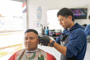 Latin barber attending a customer cutting his hair