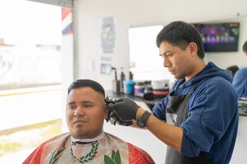 Cercles muraux Salon de beauté Latin barber attending a customer cutting his hair
