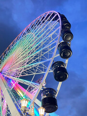 looking up at a colorful ferris wheel at night