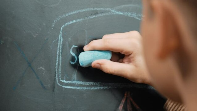 Closeup of smart student or boy hand writing prompt on blackboard. Child planing project and setting engineering system and brainstorm creative idea wrote on blackboard. Focus on hand. Erudition.