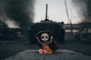 frightened doll sits on the ground surrounded by fire and smoke. A child's toy on the background of...