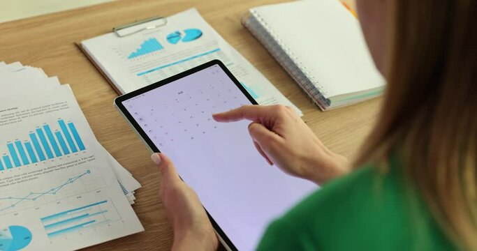 Boss woman or secretary looks at calendar on tablet screen