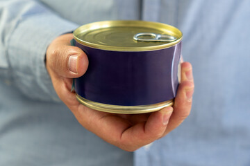 Tin can with ring in male hand. Close up. an empty label for design and text. Copy Space