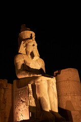 Seated statue of Ramesses II by the First pylon of the Luxor Temple, Egypt. Columns and statues of...