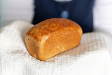 elderly grandmother treats bread. Woman hands hold bread on white towel side look domestic cozy bakery pastry warm tasty