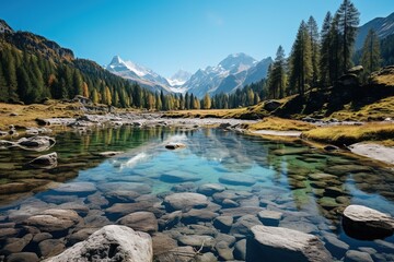 Stunning Alpine lake with crystal clear water and snow capped mountains in the distance