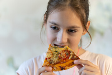 little girl keeps slice of pizza in mouth, spreads hands with hesitation, has puzzled facial expression, enjoys nice taste, wants to eat, positive woman with junk food, people and eating