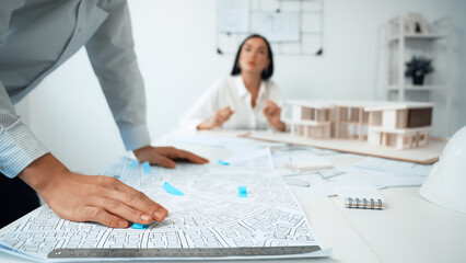 Skilled caucasian interior designer working with house model while discussing with asian architect...
