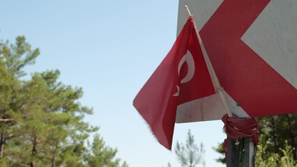 Waving Turkish flag tied to a road sign post. Independence and freedom