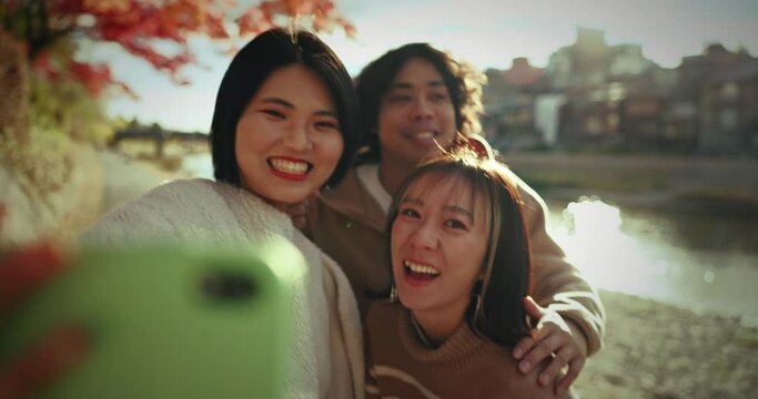 Selfie, smile and Japanese friends at river for holiday travel, fun and happy adventure together in nature. Digital photography, man and women relax on outdoor vacation with water, summer and memory.