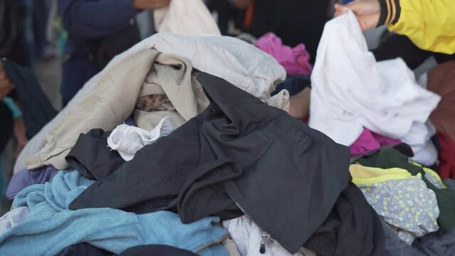 Close up of people hand choosing and buying second hand clothes in a thrift shop