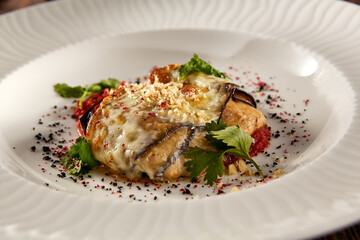 Baked eggplant roll with cheese and tomatoes, elegantly plated on a white dish