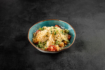Quinoa salad with grilled chicken, cherry tomatoes, and greens in a turquoise ceramic bowl