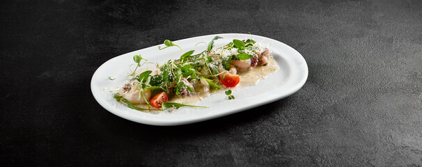 Creamy seafood assortment garnished with fresh greens and cherry tomatoes on a white oval plate