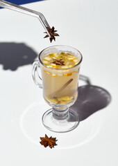 A hand delicately garnishes a glass of white mulled wine with star anise, showcasing the warmth of the spices in bright daylight