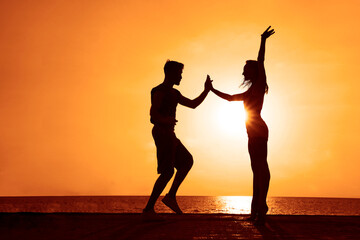 latin hispanic couple is dancing bachata salsa tango on summer beach. Sunset sky. Two hot...