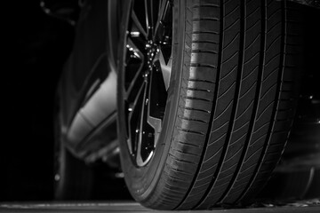 Low angle, back, rear view of a car, vehicle and its tires at the repairing shop. Concept of car maintenance service. empty Copy space. isolated on black background. night scene. - obrazy, fototapety, plakaty