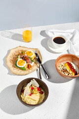 A complete breakfast set with sunny side up eggs, oatmeal, and yogurt with coffee and orange juice on a bright table