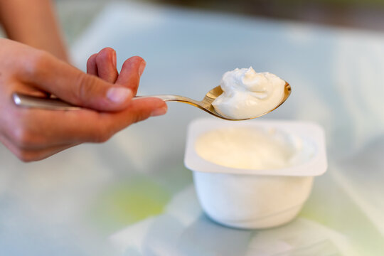 Hand holding yogurt , girl eating yoghurt. Light meal, snack. Milk product. Diet. Cream dessert.