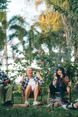 Group of man and woman friends and family singing and playing guitar during having breakfast together. People enjoy and fun outdoor lifestyle travel nature camping on summer holiday vacation.